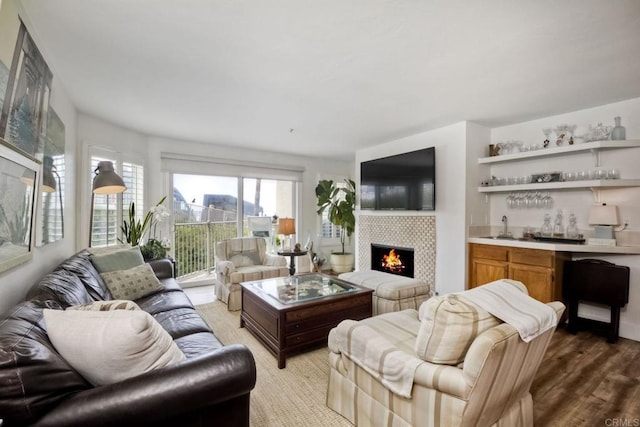 living room featuring a fireplace, wet bar, and light wood-type flooring