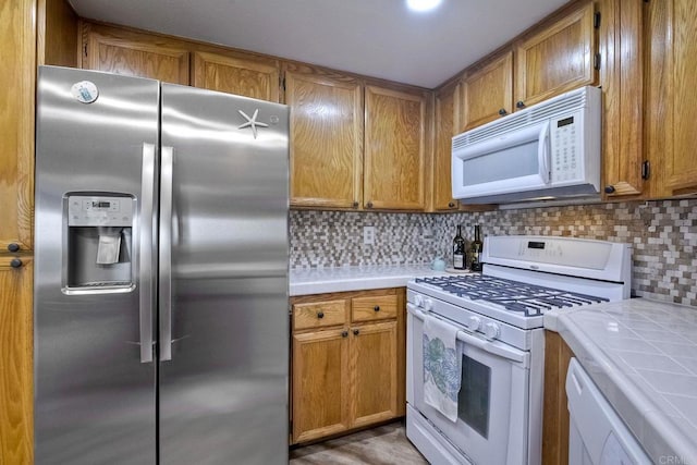 kitchen featuring tasteful backsplash, tile countertops, and white appliances