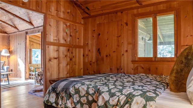 bedroom with lofted ceiling, wood walls, and multiple windows