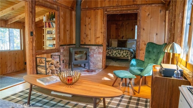 sitting room featuring hardwood / wood-style flooring, a wood stove, wood ceiling, and wooden walls