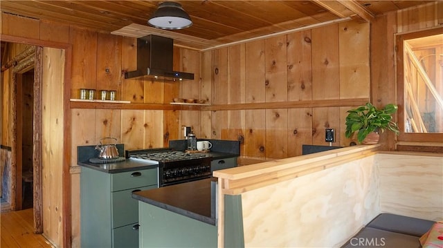 kitchen with wood walls, wooden ceiling, range, and wall chimney exhaust hood