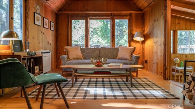 interior space featuring light wood-type flooring, lofted ceiling, and wood walls