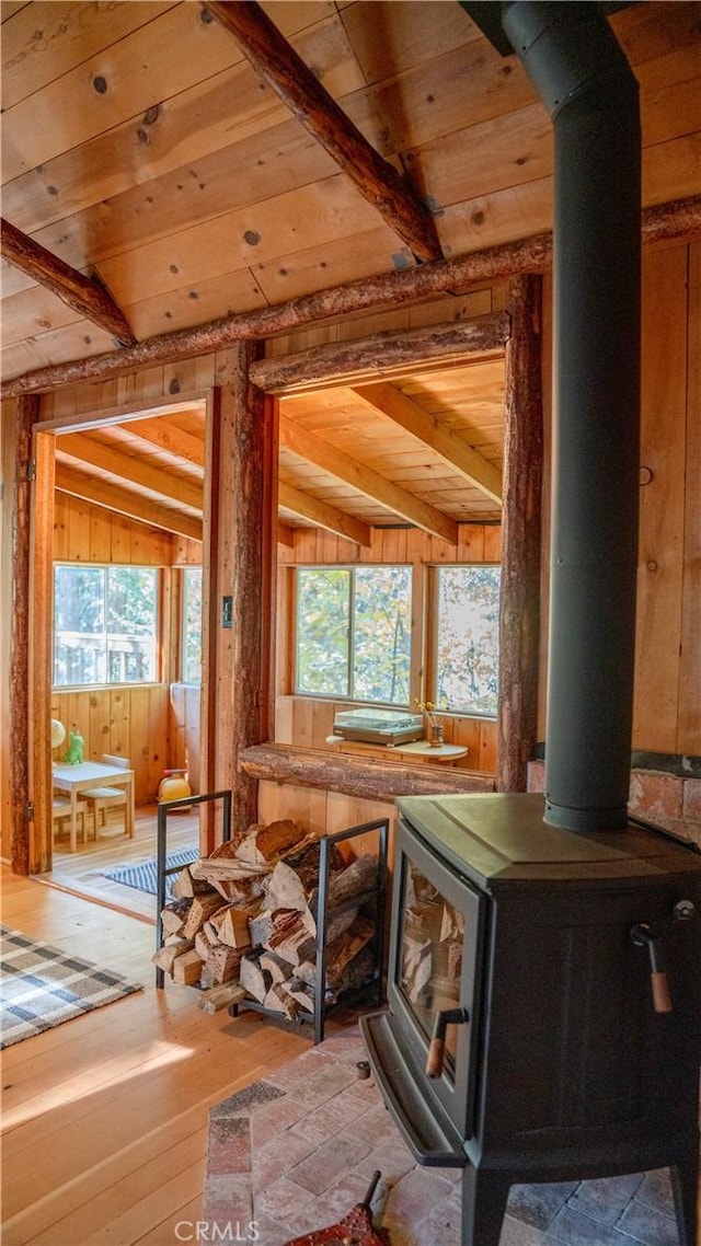 miscellaneous room with wood ceiling, wood-type flooring, wooden walls, vaulted ceiling with beams, and a wood stove