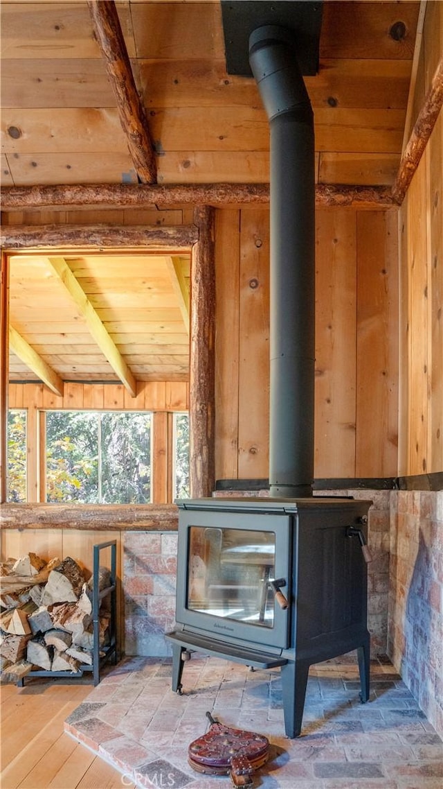 details featuring a wood stove, wood walls, and beamed ceiling