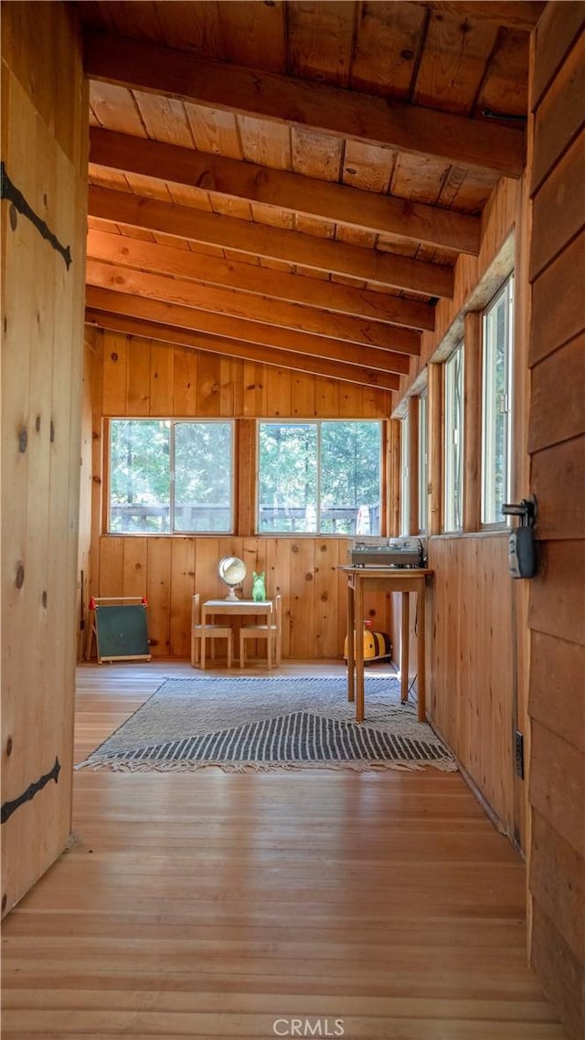 misc room with a wealth of natural light, light hardwood / wood-style flooring, and vaulted ceiling with beams