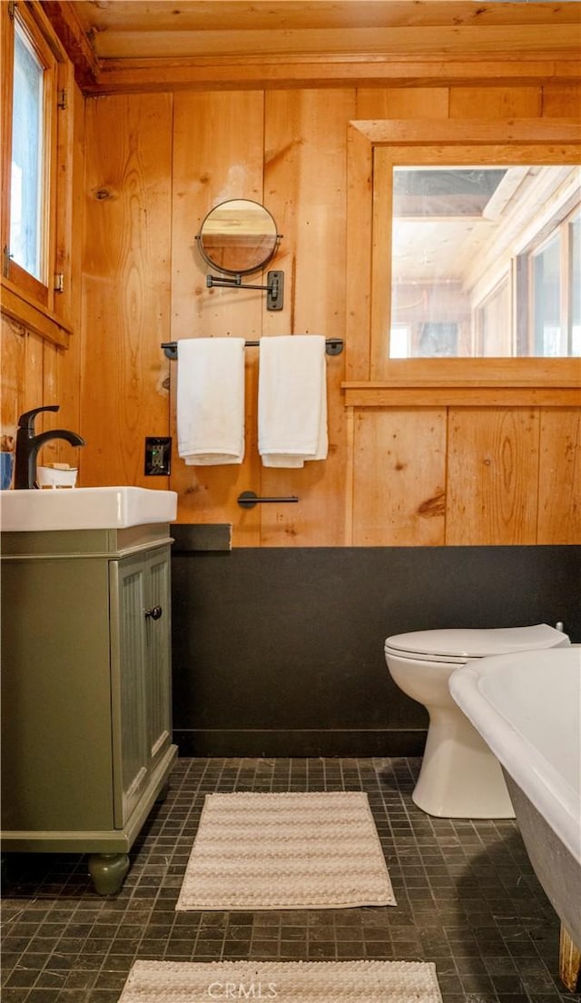 bathroom featuring tile patterned floors, toilet, vanity, and wooden walls