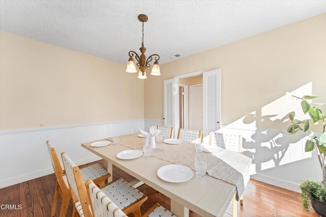 dining space featuring a notable chandelier, a textured ceiling, and hardwood / wood-style flooring