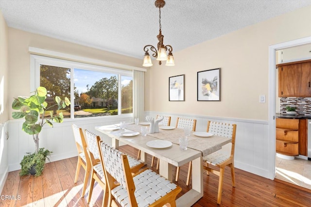 dining room with a textured ceiling, hardwood / wood-style floors, and an inviting chandelier