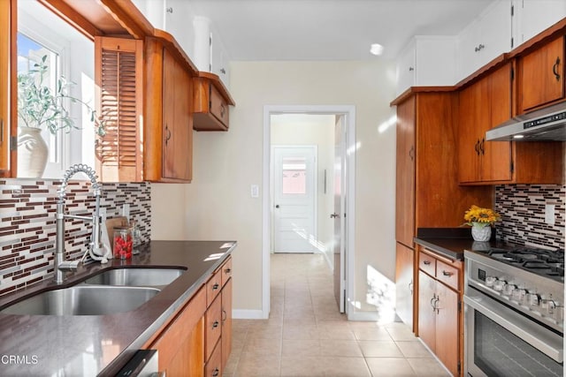 kitchen featuring light tile patterned floors, stainless steel range, backsplash, range hood, and sink