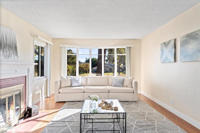 living room featuring a brick fireplace, light hardwood / wood-style floors, and a textured ceiling