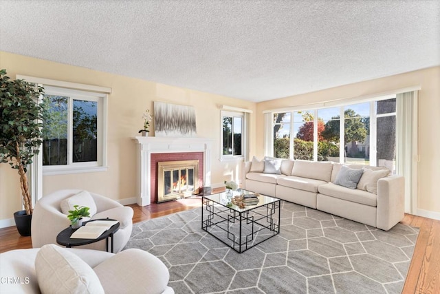 living room featuring wood-type flooring, a fireplace, and a textured ceiling