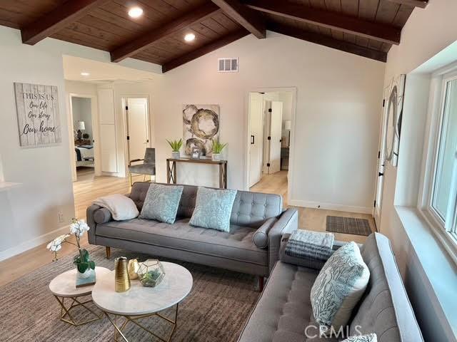 living room with wooden ceiling, light hardwood / wood-style floors, and vaulted ceiling with beams