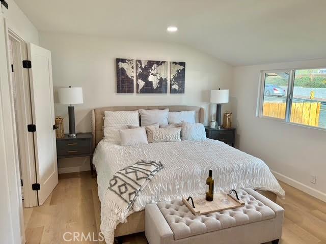 bedroom with vaulted ceiling and light hardwood / wood-style floors