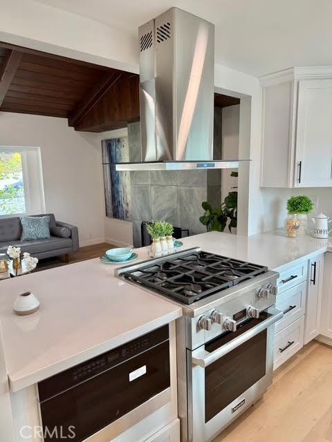 kitchen with light hardwood / wood-style floors, wooden ceiling, high end stainless steel range, wall chimney exhaust hood, and white cabinets