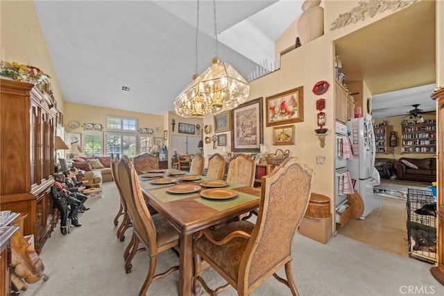 dining area with ceiling fan with notable chandelier, light carpet, and vaulted ceiling