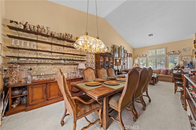 dining room with light carpet, vaulted ceiling, and a notable chandelier