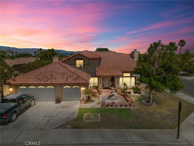 mediterranean / spanish house with a mountain view, a yard, and a garage