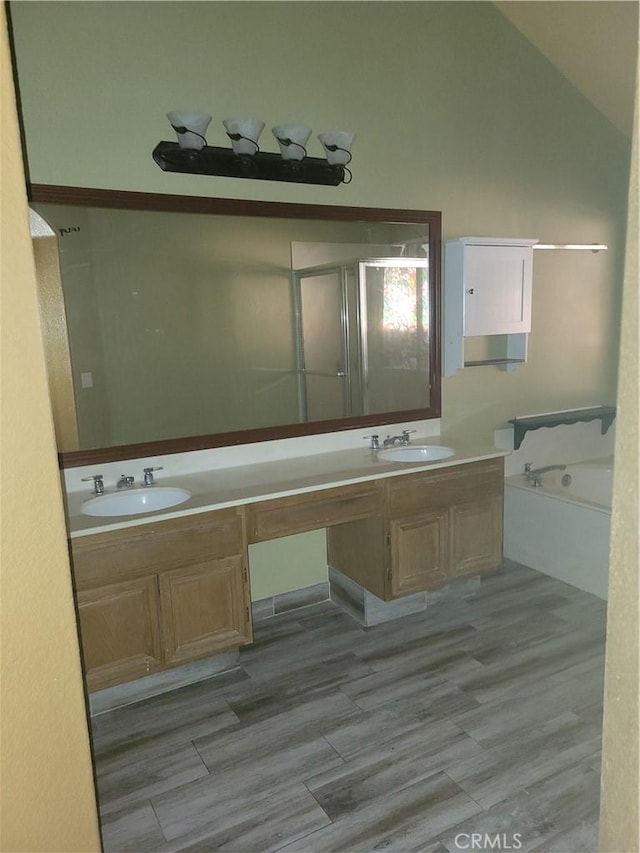 bathroom featuring plus walk in shower, lofted ceiling, hardwood / wood-style flooring, and vanity