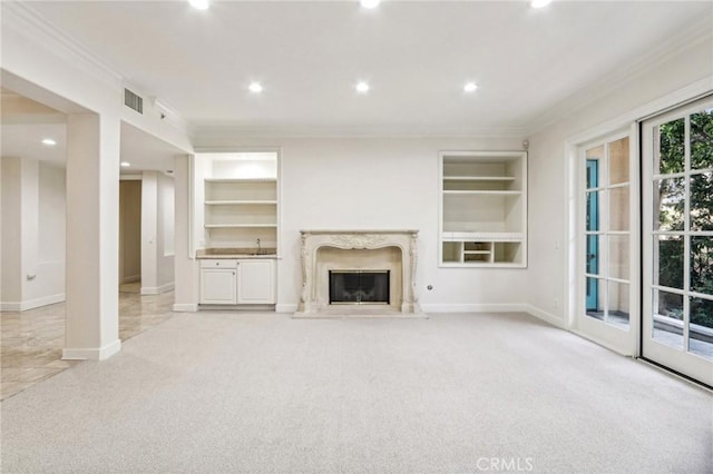 unfurnished living room featuring a fireplace, light carpet, built in features, and crown molding