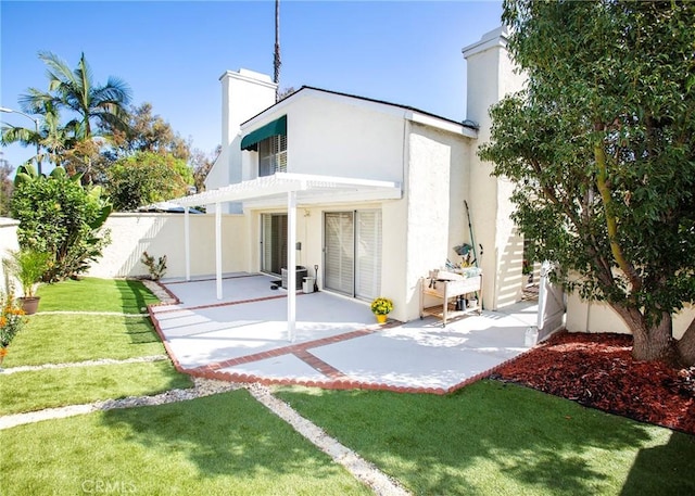 back of property with a pergola, a lawn, and a patio