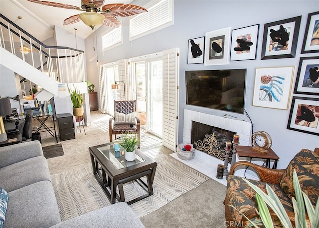 carpeted living room featuring a brick fireplace, a high ceiling, and ceiling fan