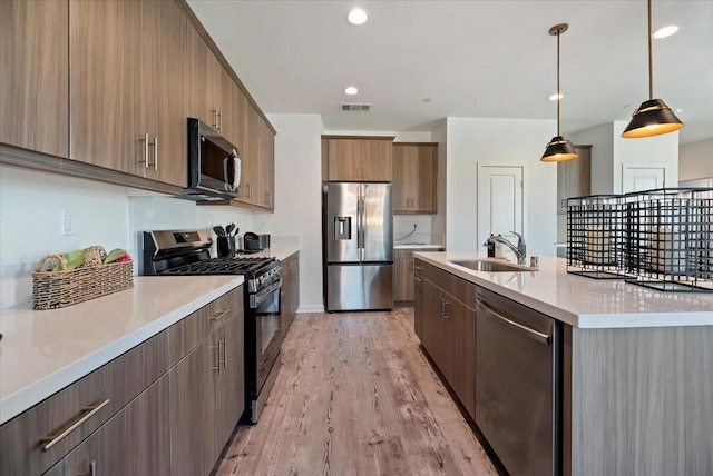 kitchen featuring a large island, appliances with stainless steel finishes, hanging light fixtures, light hardwood / wood-style flooring, and sink