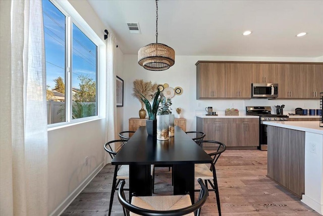 kitchen with decorative light fixtures, stainless steel appliances, and light wood-type flooring