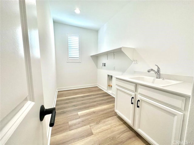 clothes washing area with electric dryer hookup, light wood-type flooring, hookup for a washing machine, cabinets, and sink