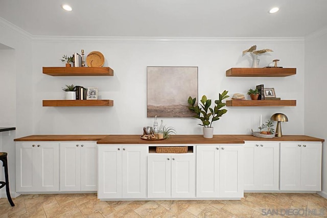 bar featuring white cabinets and ornamental molding