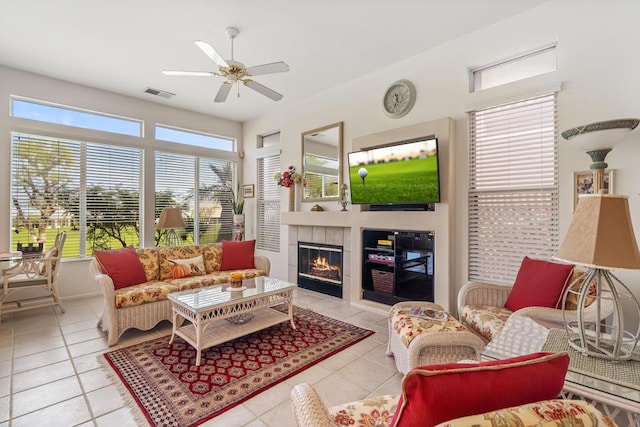 living room featuring a tile fireplace, light tile patterned floors, and ceiling fan