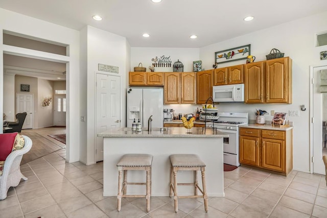 kitchen with a center island with sink, light tile patterned floors, white appliances, and sink