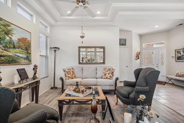 living room featuring ceiling fan, light wood-type flooring, and a towering ceiling