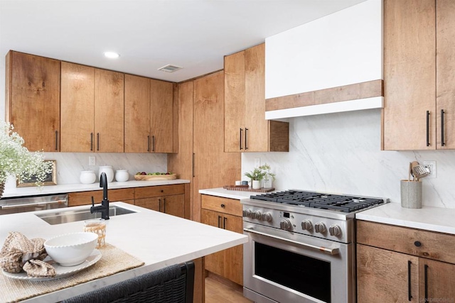 kitchen with stainless steel range, backsplash, sink, and exhaust hood