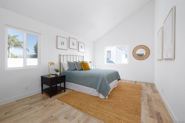 bedroom with high vaulted ceiling and light wood-type flooring