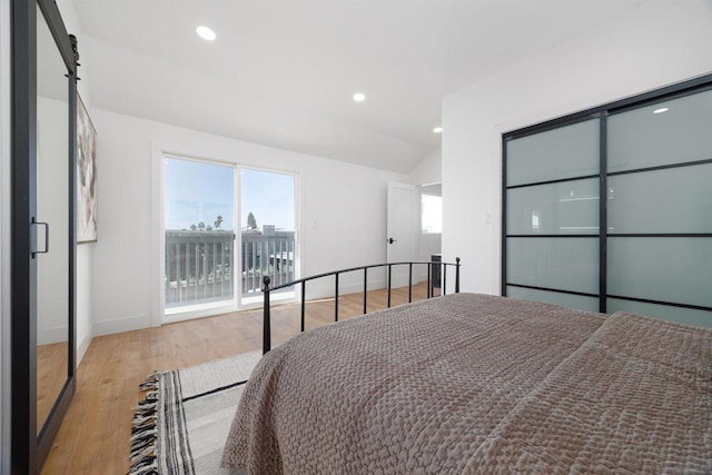 bedroom featuring light hardwood / wood-style floors, access to outside, and vaulted ceiling