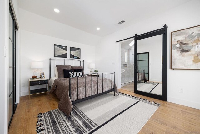 bedroom featuring a barn door and hardwood / wood-style floors