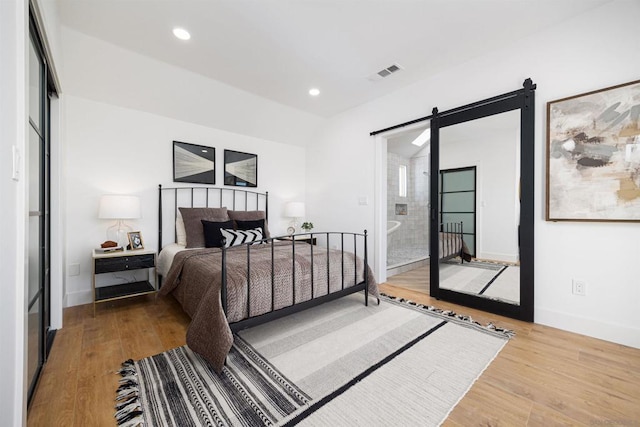 bedroom with a barn door and hardwood / wood-style flooring