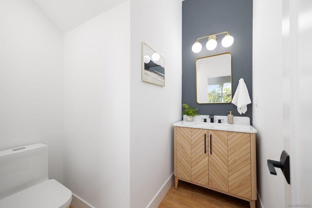 bathroom featuring toilet, vanity, and hardwood / wood-style flooring