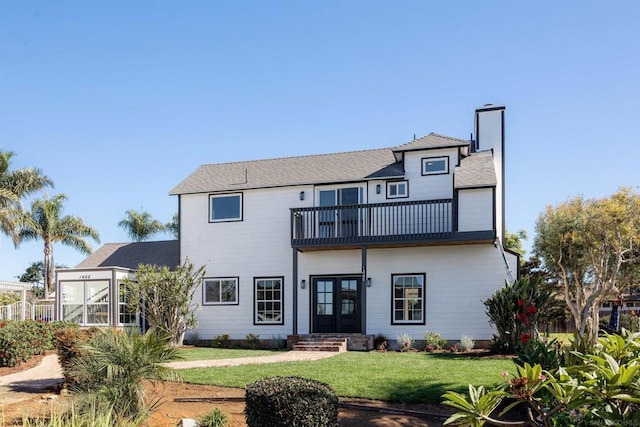 back of house featuring a balcony, a lawn, and french doors