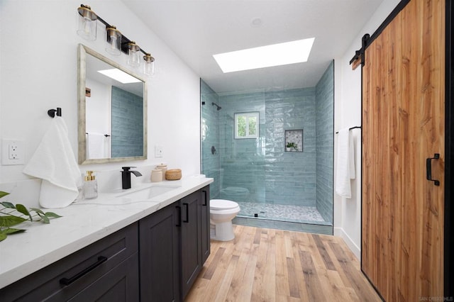 bathroom featuring an enclosed shower, wood-type flooring, vanity, a skylight, and toilet