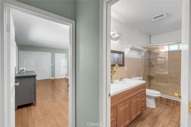 bathroom featuring vanity, toilet, hardwood / wood-style flooring, and an enclosed shower