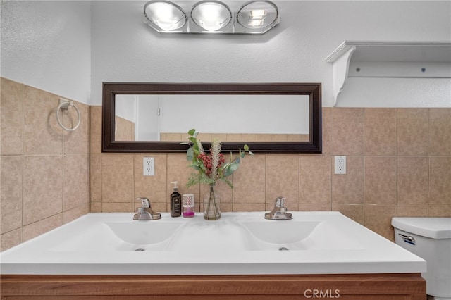 bathroom with tile walls, toilet, and vanity