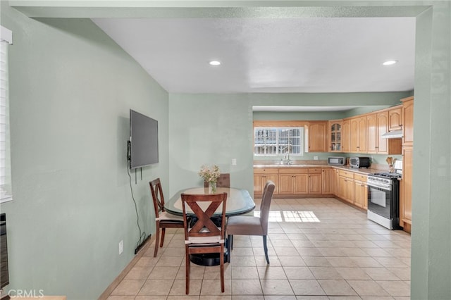 kitchen featuring light tile patterned floors, stainless steel gas stove, sink, and light brown cabinets