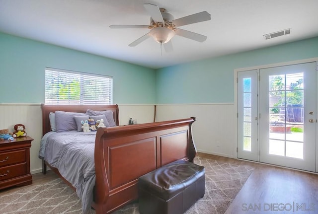 bedroom with ceiling fan, access to exterior, hardwood / wood-style flooring, and multiple windows