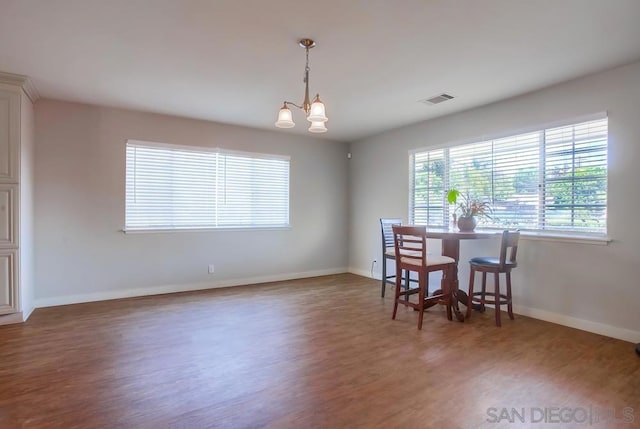 dining area featuring dark wood-type flooring and a notable chandelier