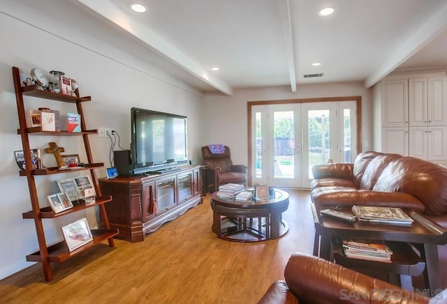 living room featuring french doors, light hardwood / wood-style flooring, and beamed ceiling