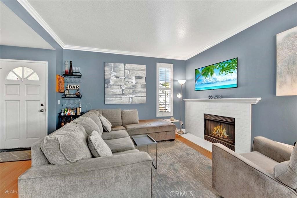 living room with crown molding, a fireplace, and hardwood / wood-style floors