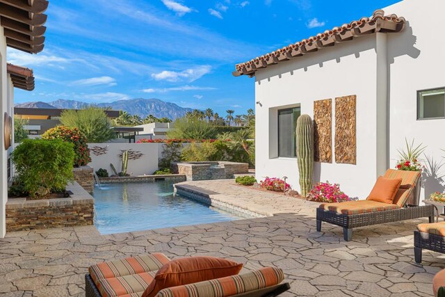 view of pool with a mountain view, an in ground hot tub, pool water feature, and a patio