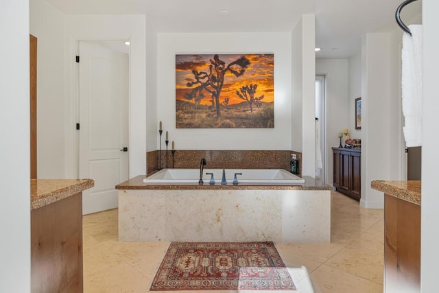 bathroom featuring vanity, tile patterned flooring, and tiled tub