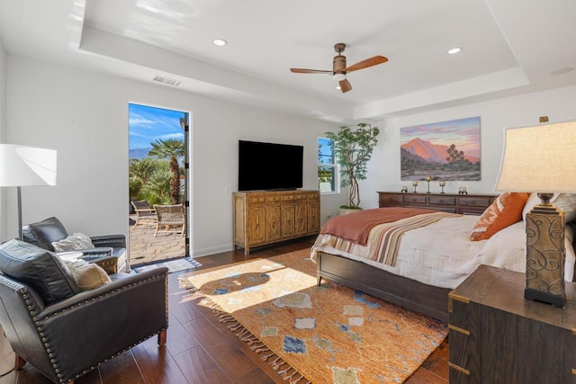 bedroom with a raised ceiling, dark wood-type flooring, access to exterior, and ceiling fan